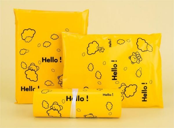 Three yellow shipping bags with playful cloud and sheep illustrations, each labeled with the word 'Hello!' in various orientations.