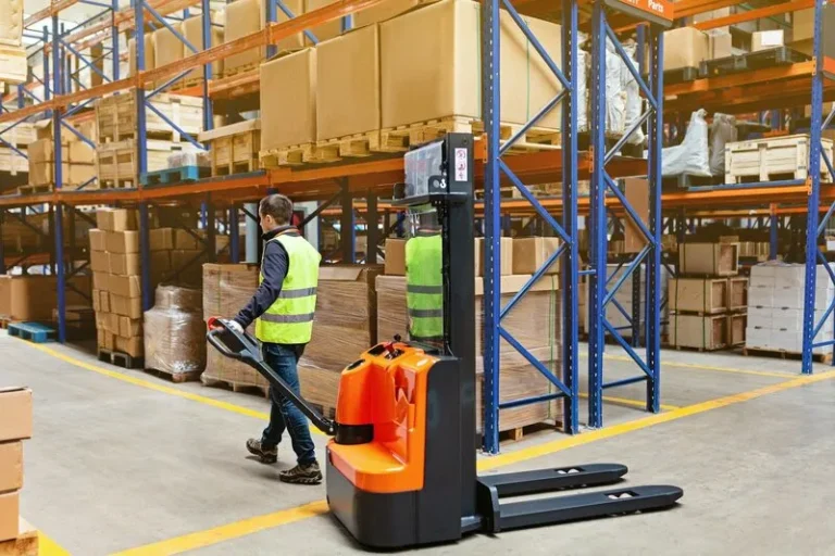 Employee working on modern warehouse and using new forklift, storehouse with shelves of goods